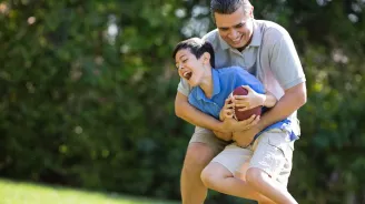 Dad playing football with son outdoors.