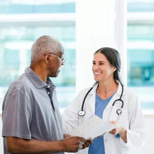 A Physician Smiles While She Goes Over a Patient's Chart With Him