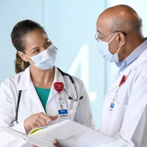 Two doctors talking while wearing masks.