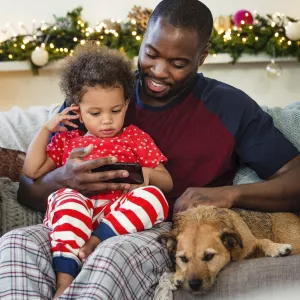 A father an son sit together on the couch during the holiday season. 