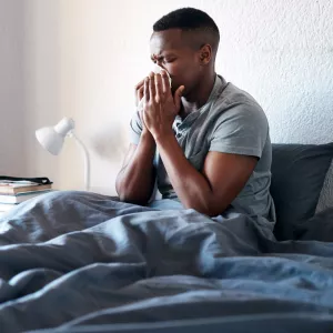Man sneezing in bed.