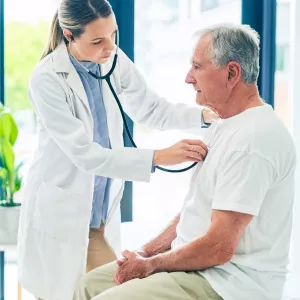 A female physician examining an older man's breathing with a stethoscope. 