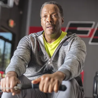 An African American man exercises on a rowing machine at the gym.