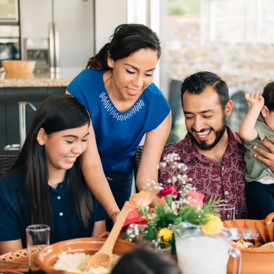 A Hispanic Family Sits Down to a Meal in Their Home.