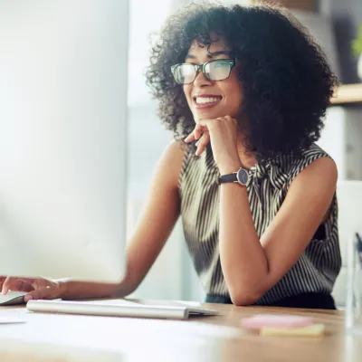 A Woman Smiles as She Reads on Her Computer at Home.