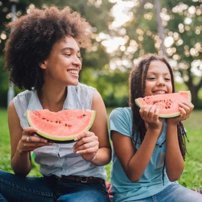 A Mother and Daughter Sit at a Picnic Enjoying Fruit