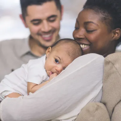 A New Mom Holds Her Baby While While Her Husband Smiles