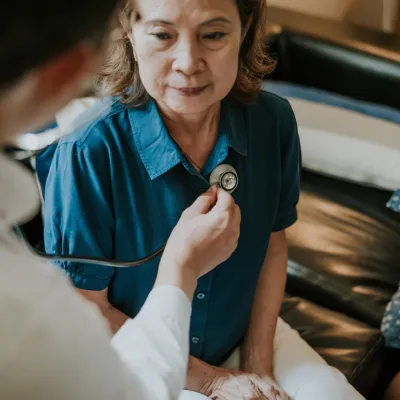 A Doctor Checks the Breathing of a Female Patient With a Stethoscope in an Office