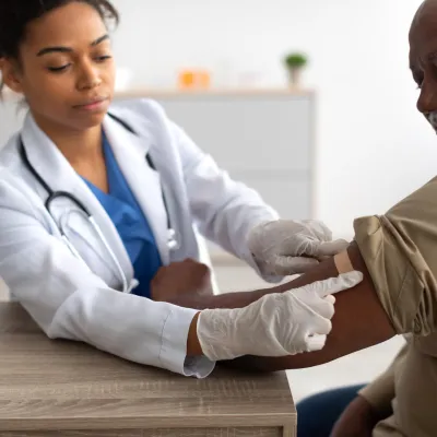A Physician Puts a Bandage on an Injection Site After a Vaccine