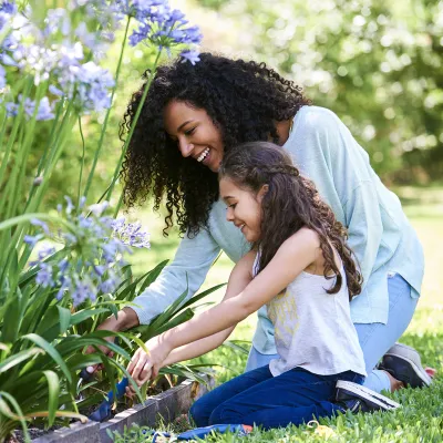 A girl and her mother planting flowers.
