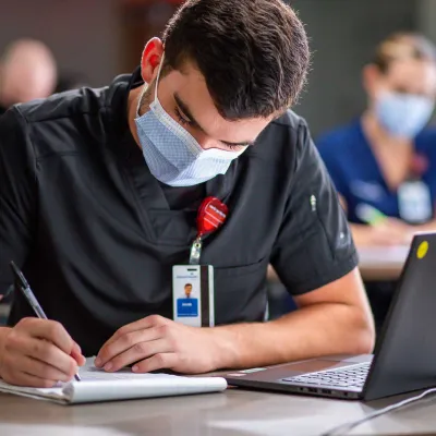 An AdventHealth nurse writing in his notepad
