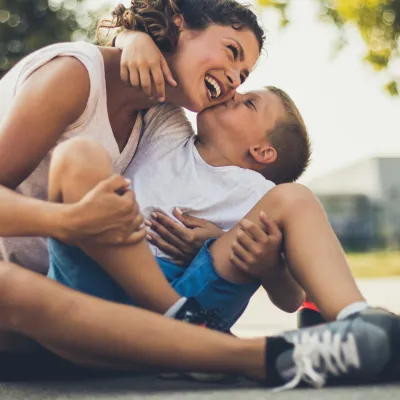 A mother and son take a water break on the basketball court during the summer.