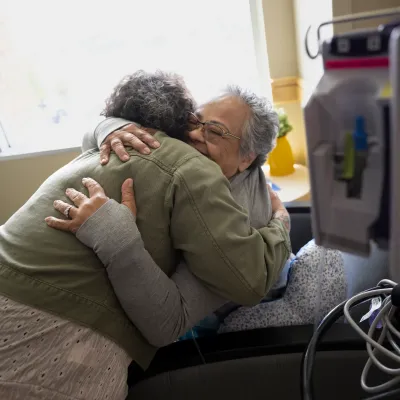 Woman comforting senior patient in hospital.