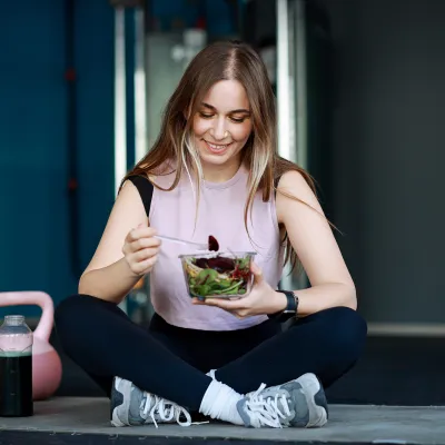 Woman eating salad after excercising.