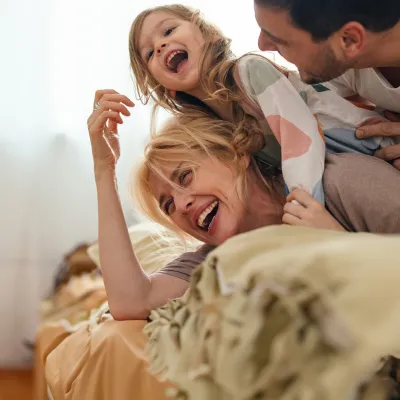 Family Laughing Together While Laying on a Bed