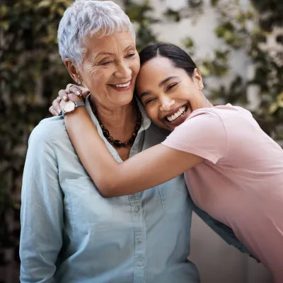 A Woman Hugs her Grandmother Outside in the Garden