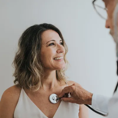 Doctor Listening to Female Patient Heartbeat