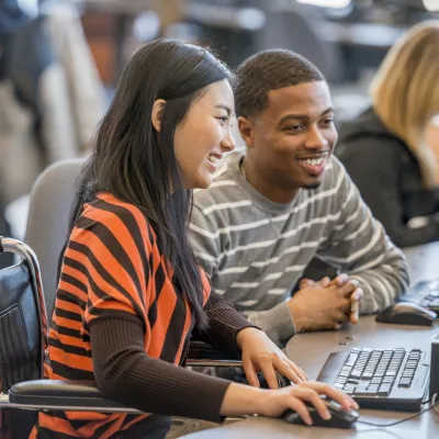 Boy Student Helping Girl With Wheelchair Search on Computer
