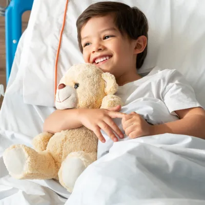 A little boy hugs his teddy bear while in the hospital.