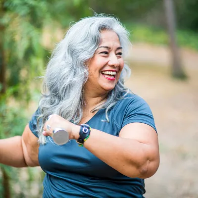 An overweight senior hispanic woman uses weights while she exercises