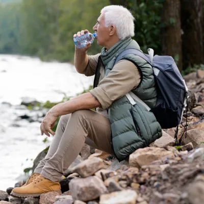A man taking a water break on a hike.