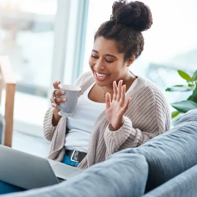 A woman waving to a friend on a video call. 