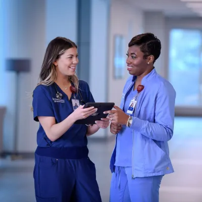 Nurses Looking at Each Other Holding Tablet