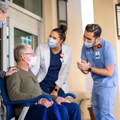 Nurses Helping Patient in Wheelchair Just Outside of the Hospital