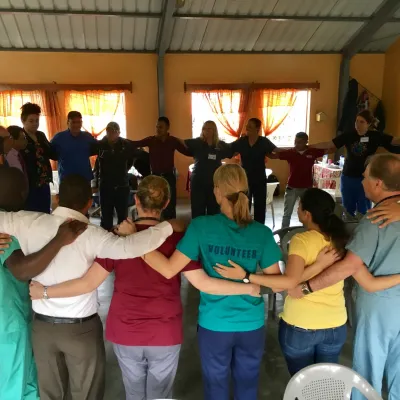 A group of physicians, nurses, and others in a group circle