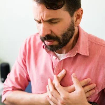 A main sitting and placing hands over chest in pain.