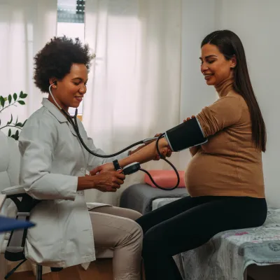 Pregnant woman getting her blood pressure checked by a physician