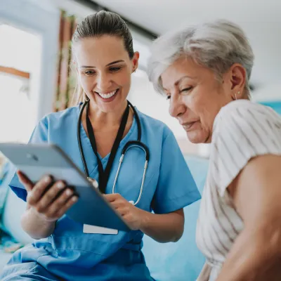 Nurse showing female patient tablet.