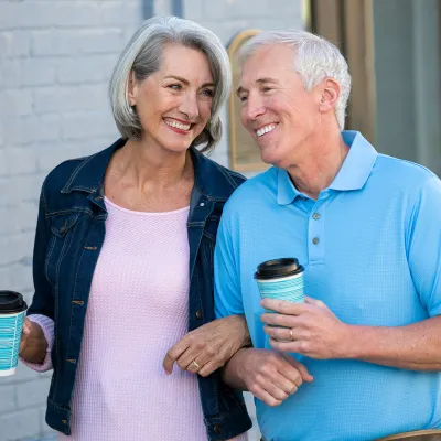 Older couple walking with coffee