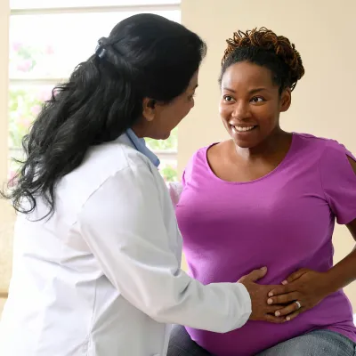 A nurse having a friendly conversation with a patient who is expecting a baby. 