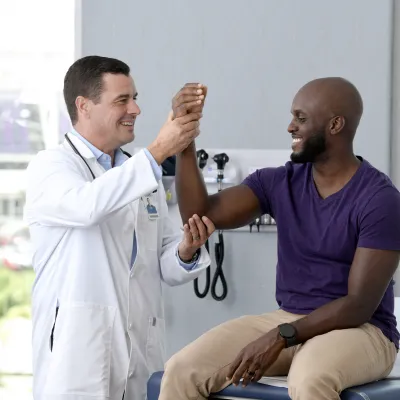 A Provider Checks a Patient's Elbow Joint in an Exam Room
