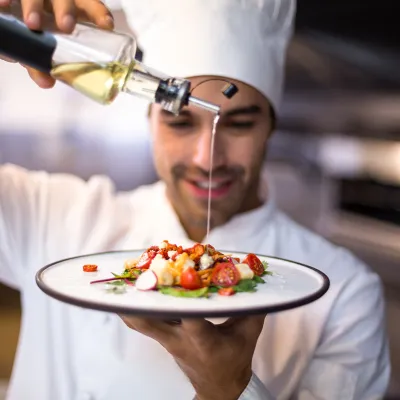 Male Chef drizzling olive oil on plate