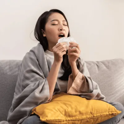 A woman sneezing into a tissue.