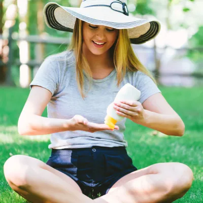 Woman Applying Sunscreen in Park