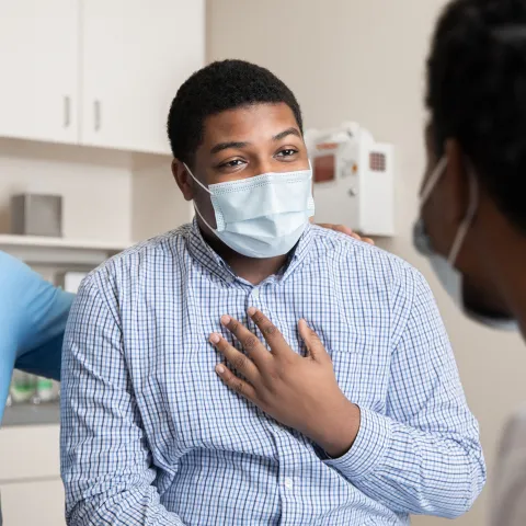 A Man Speaks to His Doctor in a Patient Room While Being Comforted with a Family Member.