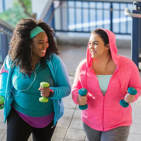 Two Women Running Outside With Weights