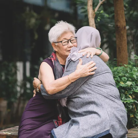 Two Women Embrace Outside in a Beautiful Nature Setting.