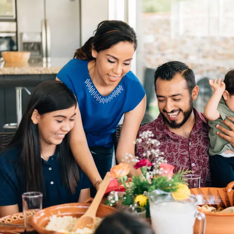 A Hispanic Family Sits Down to a Meal in Their Home.