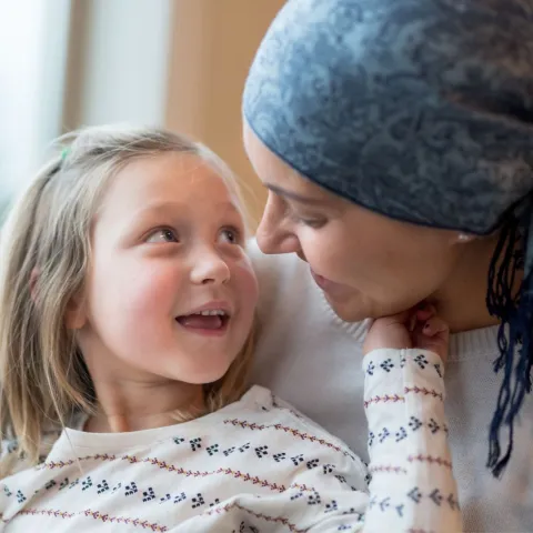 A Small Child Smiles and Touches Her Mother's Face While Sitting in a Window.