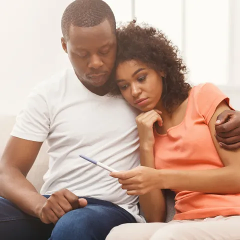 A Couple Embraces While Waiting for the Results of a Home Pregnancy Test.