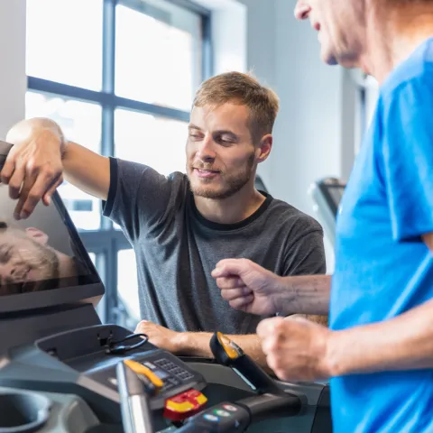A Trainer Sets Up a Treadmill for a Patient