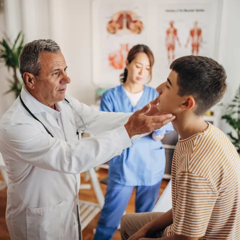 A Doctor Examines a Teenage Patients Face While a Nurse Takes Notes