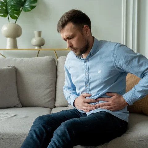 A Man Winces in Pain as He Hold's his Side