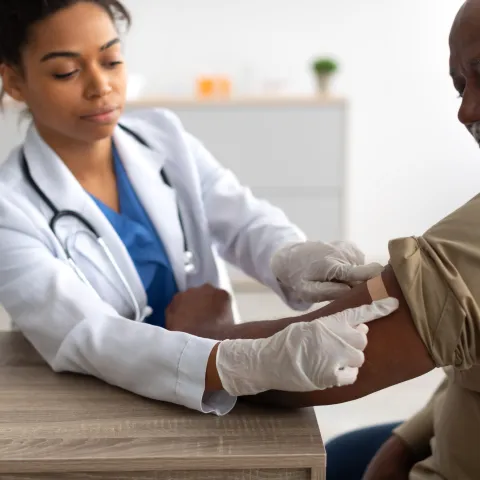 A Physician Puts a Bandage on an Injection Site After a Vaccine