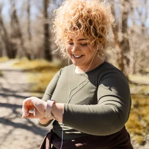 A Woman Checks Her Smart Watch While Going For a Run in the Park