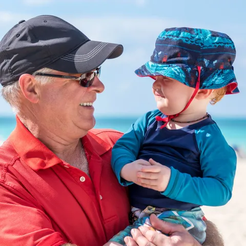 A Grandfather Holds His Grandson on the Beach